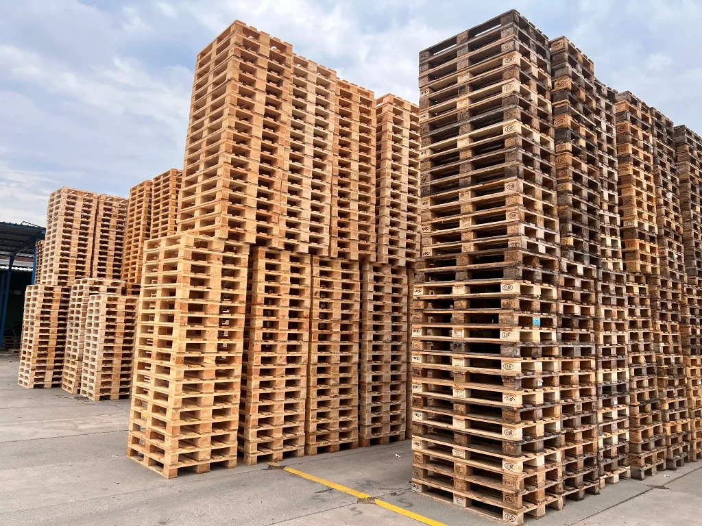 Tall stacks of wooden pallets stored in an outdoor yard.