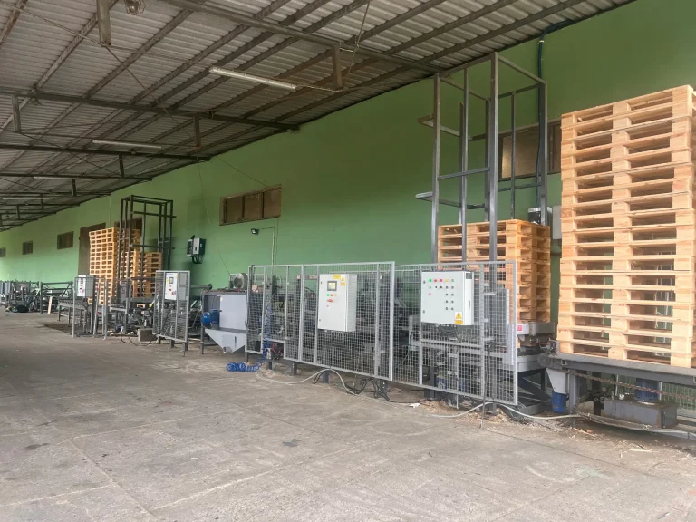Forklift moving pallets near a truck and warehouse loading area.
